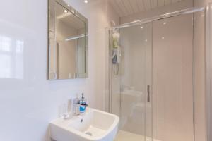 a white bathroom with a shower and a sink at Kingsley Guest House in Edinburgh +40 photos