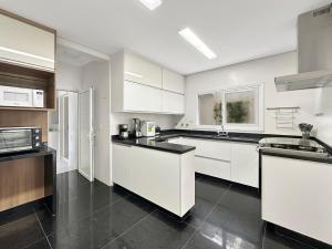 a kitchen with white cabinets and black counter tops at Suíte Piscina e Churrasqueira AC Acesso a Praia in Guarujá