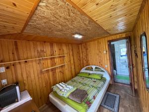 a small bedroom with a bed in a wooden room at Садиба «Під ліском» in Pulʼmo