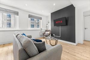 a living room with a couch and a tv on a wall at Heart of the City Centre - Serviced Apartments in Manchester