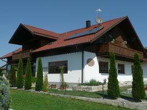 Biały dom z czerwonym dachem i drzewami w obiekcie Privatpension Eberth w mieście Bogen