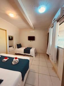 een hotelkamer met twee bedden en een tv bij Shalon Adonai by Martinelli in Fernando de Noronha