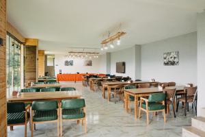 a dining room with wooden tables and green chairs at Yege Villa Bungalov in Çamlıhemşin