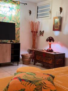 a bedroom with a bed and a tv and a table at La Kaza Tresor - Appartement T2 spacieux avec jacuzzi privé in Sainte-Anne