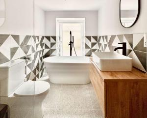 a bathroom with a tub and a toilet and a sink at The Old Dairy Barn - Stunning Rural Retreat in Kirkby Stephen