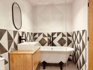 a bathroom with a tub and a sink and a mirror at The Old Dairy Barn - Stunning Rural Retreat in Kirkby Stephen