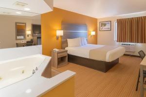 a hotel room with a bed and a bath tub at Travelodge by Wyndham Muskegon in Muskegon +28 photos