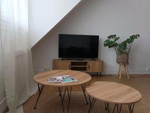 a living room with a table and a tv at Appart Cosy à Beauvais Hyper Centre proche Aéroport et Gare SNCF in Beauvais