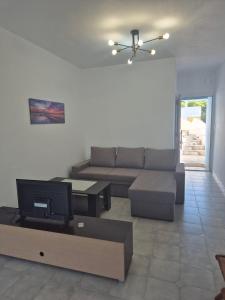 a living room with a couch and a tv at Deco Apartments Aigina in Vaia