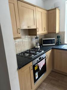 a kitchen with wooden cabinets and a stove top oven at Entire 2-Bedroom House Dudley in Sedgley