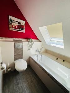 a bathroom with a white toilet and a red wall at Ferienwohnung Sternfeld in Osburg +19 photos