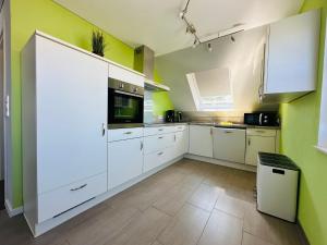a large kitchen with white cabinets and green walls at Ferienwohnung Sternfeld in Osburg