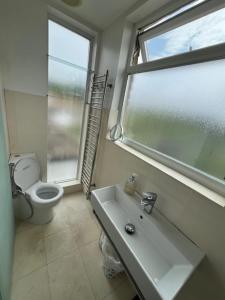 a bathroom with a toilet and a sink and a window at 4 to 5 Bedroom beautiful holiday home London sleeps 9-central Links in London