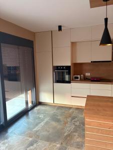 a kitchen with white cabinets and a large glass door at Vila Enesa in Dobra Voda