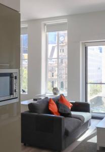 a black couch in a living room with windows at The Clocktower Light and Airy Studio on Bourke St in Melbourne