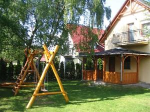 un cortile con parco giochi di fronte a una casa di 14 férőhelyes ház saját stéggel, játszótérrel Balatonfenyvesen vízparti utcában a Balatonfenyves