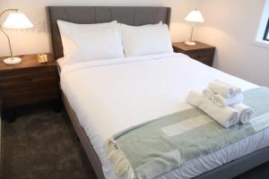 a bedroom with a large white bed with towels on it at Cosy 2BR House in Awaroa Road in Auckland