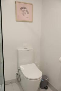 a white bathroom with a toilet and a picture on the wall at Cosy 2BR House in Awaroa Road in Auckland +17 photos
