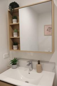 a bathroom sink with a large mirror above it at Cosy 2BR House in Awaroa Road in Auckland