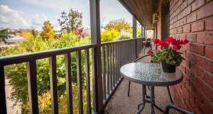 een tafel met rode bloemen op een balkon bij Armour Motor Inn in Beechworth +11 foto's