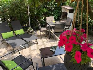 a patio with chairs and a table with red flowers at Appartamento villatorretta24 in Riva del Garda