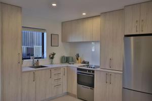 a kitchen with wooden cabinets and stainless steel appliances at Cosy 2BR House in Awaroa Road in Auckland +25 photos