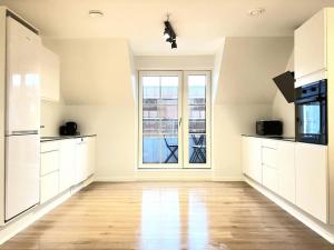 an empty kitchen with white cabinets and a large window at Spacious Apartment for 4 in Esbjerg