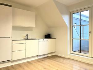 an empty kitchen with white cabinets and a window at Spacious Apartment for 4 in Esbjerg