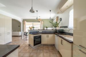Una cocina con gabinetes blancos y encimeras negras. en Villa ROMARY Piscine & Proche Centre Saint Rémy de Provence, en Saint-Rémy-de-Provence 10 fotos más