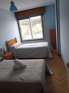 a room with three beds and a window at Apartamento Playa de Covas in Viveiro