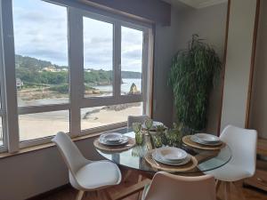 a dining room with a table and chairs and a window at Apartamento Playa de Covas in Viveiro