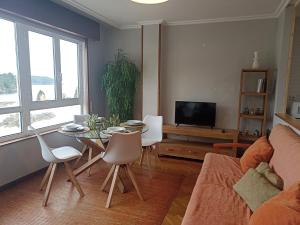 a living room with a table and chairs and a tv at Apartamento Playa de Covas in Viveiro