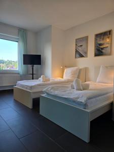 two beds in a room with a window at APARTMENT PD23 ALTE FEUERWACHE I Ganze Wohnung I 5 Einzelbetten I 3 Zimmer I 3min CityHospital I 50m Supermarkt I Küche I SmartTV in Ibbenbüren