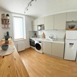 a kitchen with white cabinets and a wooden floor at Le Cocon de KENNA au centre du bourg in Dompierre-sur-Besbre