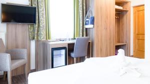 Zimmer mit einem Bett und Stühlen sowie einem TV in der Unterkunft Hotel Marko in Sankt Kanzian am Klopeiner See