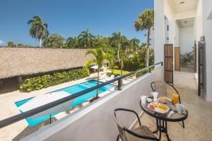a balcony with a table and chairs and a swimming pool at La Curadiña - Encuentro Surf Hotel in Cabarete