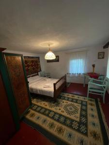 a bedroom with a bed and a chair and a window at Căsuța de Sub Deal in Lunca