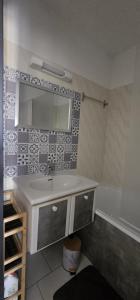 une salle de bains avec lavabo, miroir et baignoire dans l'établissement La Dolce Vita, à Balaruc-les-Bains