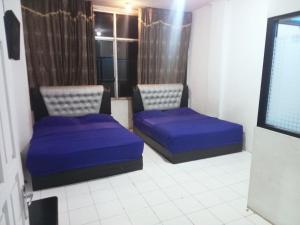 a room with two blue beds and a tv at Nafisha Hotel Bukittinggi in Bukittinggi