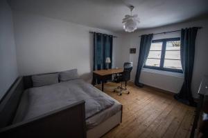 a bedroom with a bed and a desk and a window at Casa cu copaci Romanian historical farmhouse in Mărişel