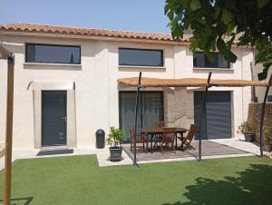 a house with a table and chairs in a yard at VILLA entière LA BERGERIE in Narbonne