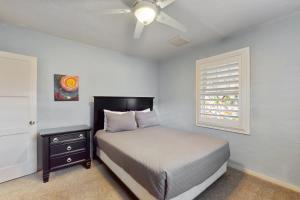 Schlafzimmer mit einem Bett, einem Deckenventilator und einem Fenster in der Unterkunft Living the Coronado Dream in Phoenix