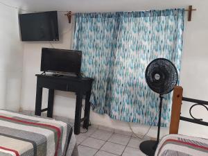a room with a fan and a table with a television at Affordable and Peaceful – Olas in Manzanillo