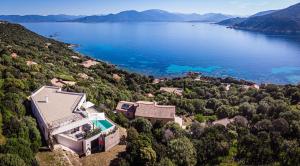 una vista aerea di una casa su una collina vicino a un lago di Villa d'architecte classée 5 étoiles a Campomoro