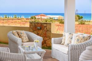eine Terrasse mit 2 Stühlen, einem Tisch und Meerblick in der Unterkunft Ammos Boutique Apartments & Suites in Malia