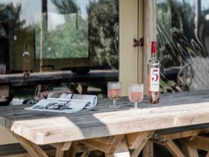 Una botella de vino y dos copas en una mesa de madera. en Lodge Tent in Callantsoog by Dunes, en Callantsoog