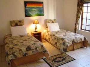 a bedroom with two beds and a lamp on a tiled floor at Louhallas Accommodation in Edenvale