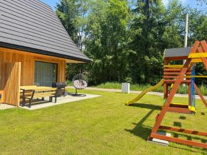 a playground with a slide and a bench and a house at Młyńska Chata in Poronin
