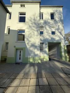 un gran edificio blanco con una sombra en él en Apartment Borsdorf 2 R, en Leipzig