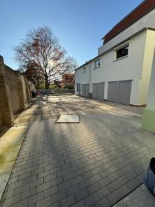 Un camino de entrada de ladrillo con un edificio y un árbol. en Apartment Borsdorf 2 R, en Leipzig